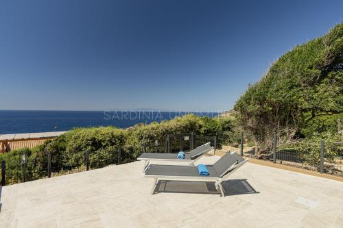a patio with two lounge chairs and the ocean at Villetta Luce Marina in Costa Paradiso