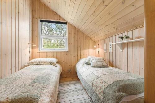 two beds in a room with wooden walls and a window at 8923-Allingabro-Poppelvej-17 in Allingåbro