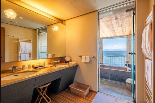 ein Badezimmer mit Waschbecken und großem Spiegel in der Unterkunft Awashima Hotel in Numazu