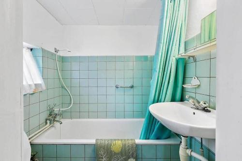 a blue tiled bathroom with a sink and a tub at 1102-N-Hundested-Skansevej-45 in Hundested