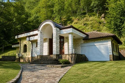 a house with a garage and a hill at Guest House Fedor in Ribarica