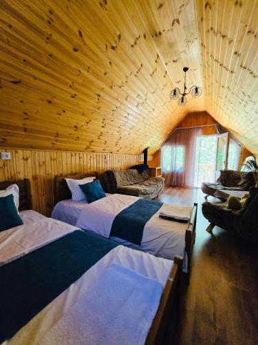 a bedroom with two beds in a room with wooden walls at DEDULETI დედულეთი in Ambrolauri