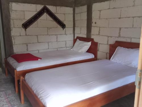 two beds in a room with a brick wall at Komachi House in Limbung