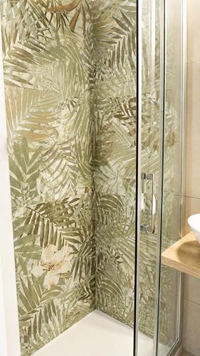 a shower with a glass door with a green wallpaper at Rallenta Casamassima in Casamassima