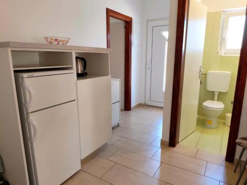 a kitchen with a white refrigerator and a toilet at Apartments Pine in Primošten