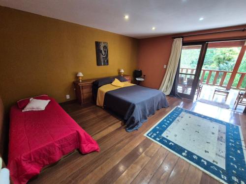 a bedroom with two beds and a balcony at Casa de Araras in Araras Petropolis