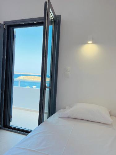 a bedroom with a bed and a large window at Theros (Θέρως) in Batsi