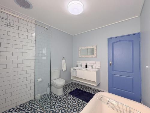 a bathroom with a toilet and a sink and a blue door at Swordfish Retreat in St. Helena Bay