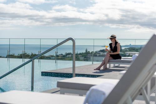 a woman sitting on a bench next to a swimming pool at Doubletree By Hilton Lagoa Azores in Lagoa