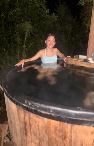 a young girl is sitting in a hot tub at Cabañas Troncos de Relin in Panguipulli