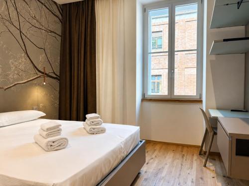 a hotel room with two beds and a desk and a window at Luxury Lodge - Moderno Residence vicino alla Stazione in Trieste