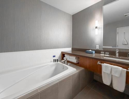 a bathroom with a large tub and a sink at Coast Coal Harbour Vancouver Hotel by APA in Vancouver