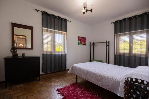 a bedroom with a bed and two windows and a mirror at Casa de Jonathan in Vilarinho do Souto