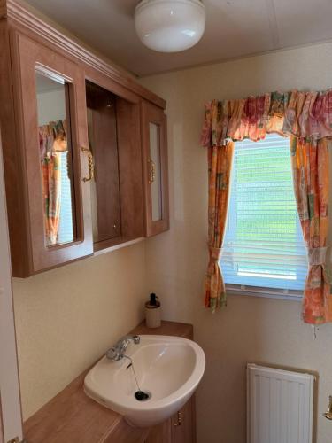 a bathroom with a sink and a window at Swans Rest - Lakeside Caravan Park in Denver