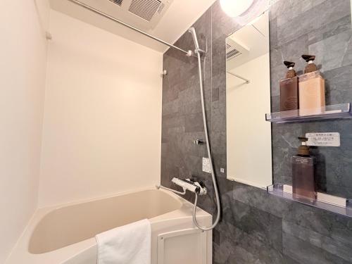 a bathroom with a bath tub and a mirror at LuxuryHOTEL難波南 in Osaka