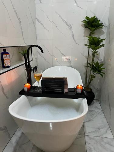 a bath tub in a bathroom with a glass of wine at Modern 3BR Smart Villa near Lekki Conservation with Inverter PS5, Hot Tub and Gym in Ibeju