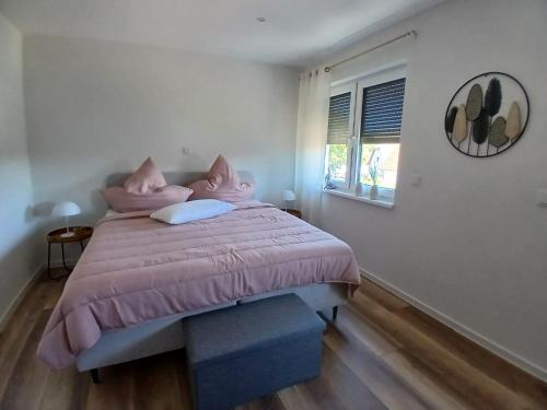 a bedroom with a bed with pink pillows and a window at Ferienwohnung Sägmühlweiher in Ludwigswinkel