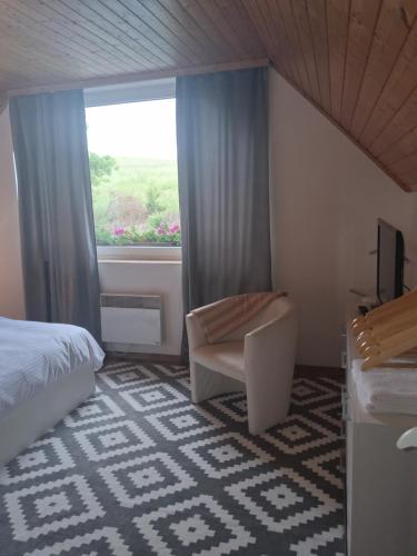 a bedroom with a bed and a window and a chair at Pod jedľou in Liptovský Trnovec