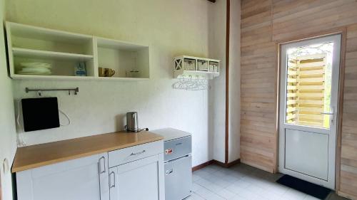 a kitchen with white cabinets and a television and a window at Luokesų Dvaro sodyba in Ažuluokesa