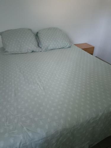 a white bed with two pillows on top of it at Chambre des Iris in Graveson