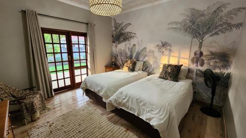 two beds in a room with palm trees on the wall at FinchDen House in Bulawayo