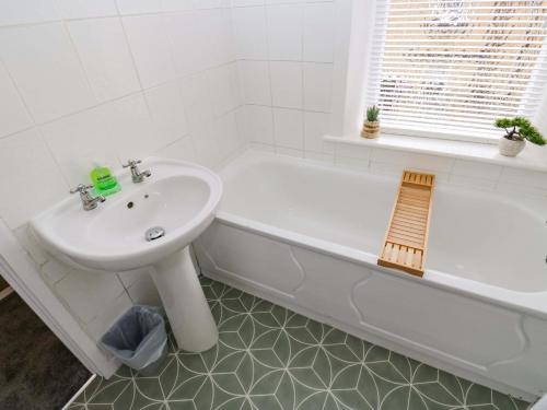 a white bathroom with a sink and a bath tub at Saltaire House in Saltaire