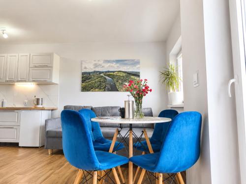 a kitchen and dining room with a table and blue chairs at Willa Panorama 881-751-206 in Polańczyk