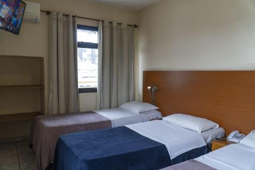 a hotel room with two beds and a window at Hotel Vila Rica Flat in Resende