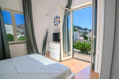 a bedroom with a bed and a balcony with a television at Casa Ginevra Capri in Capri