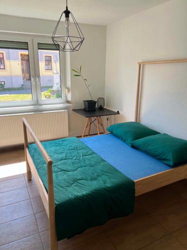 a bedroom with a bed with green sheets and a window at Hospodářství u kapličky in Kladeruby nad Oslavou