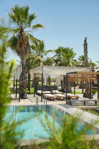 a swimming pool with a gazebo and palm trees at Ayvalık Sea Long in Ayvalık