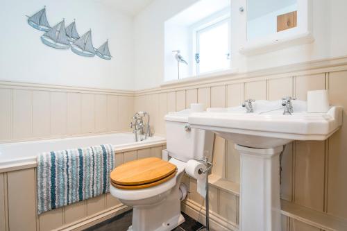 a bathroom with a toilet and a sink and a tub at Delfryn in Tenby