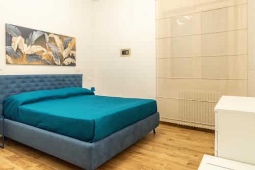 a bedroom with a blue bed and a painting on the wall at La Casa al Centro in Policoro