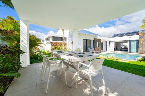 a white table and chairs on a patio with a pool at Villa Solis - Elegant & Modern Private Pool Escape in Cap Malheureux