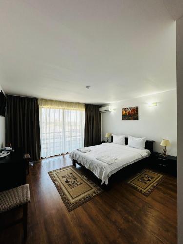 a bedroom with a white bed and a large window at pensiunea delta ideal in Sulina