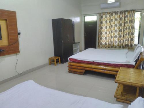 a room with two beds and a tv and a table at Natraj hotel rooms and restaurant in Motīnāla