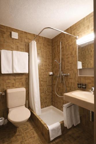 a bathroom with a shower and a toilet and a sink at Hotel Alpina Parpan in Parpan