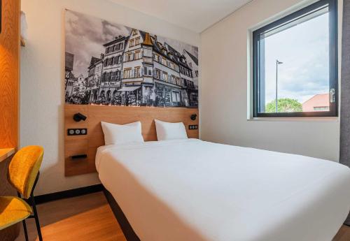 a bedroom with a large white bed and a window at B&B HOTEL Colmar Expo in Colmar