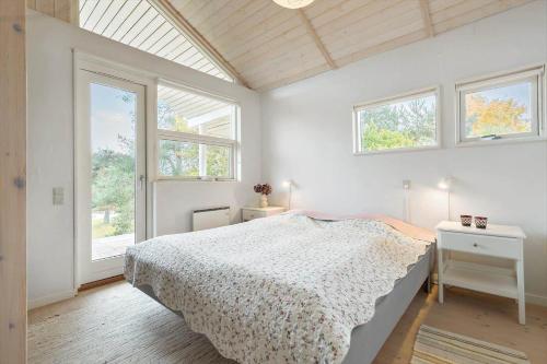 a white bedroom with a bed and two windows at 84174-Knebel-Fuglsovig-301 in Knebel