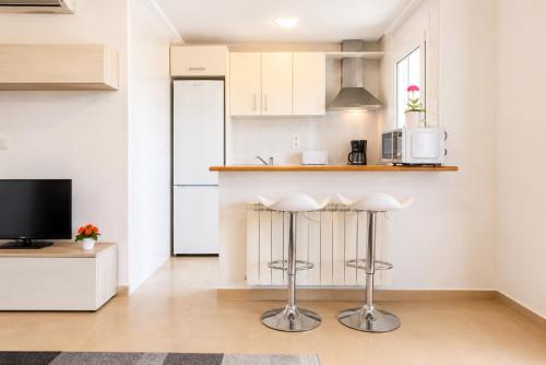 a kitchen with white cabinets and bar stools at Adosado Roldán by Rental Olé in Roldán