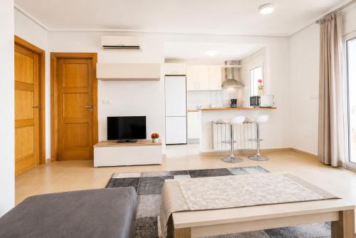 a living room with a table and a tv at Adosado Roldán by Rental Olé in Roldán