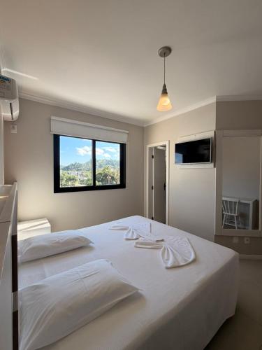 a bedroom with a large white bed with a window at Hotel Castelo in Gravatal