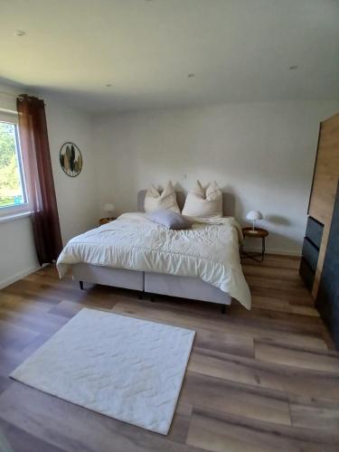 a bedroom with a bed with white sheets and a rug at Ferienwohnung Skulpturenweg in Ludwigswinkel