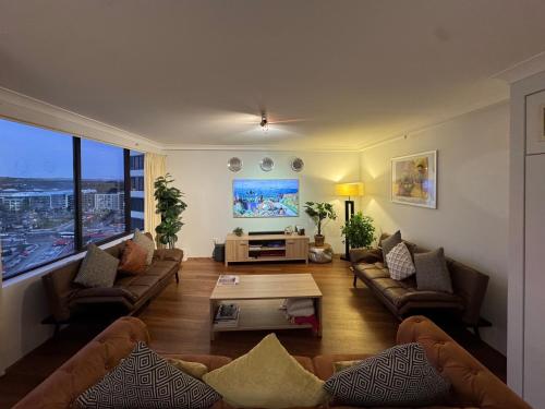 a living room with couches and a large window at Canberra City View Apartment in Canberra