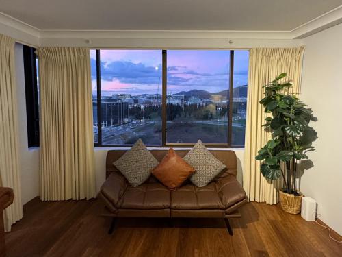 a living room with a couch and a large window at Canberra City View Apartment in Canberra