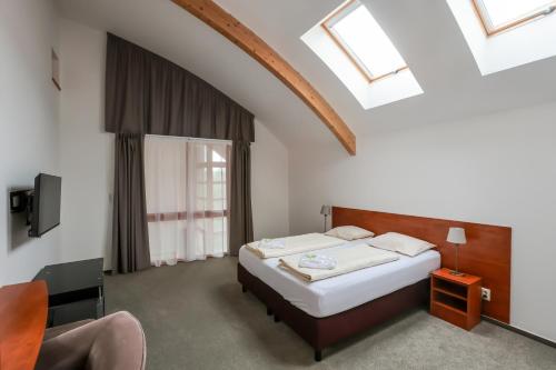 a bedroom with a bed and a chair and a window at Lipno Lake Resort in Lipno nad Vltavou