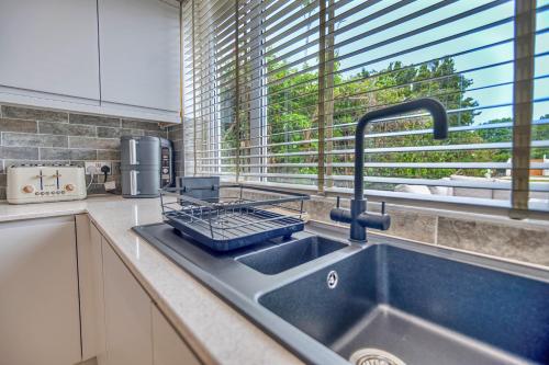 a kitchen counter with a sink and a window at Finest Retreats - Dockyard House in Pembroke Dock