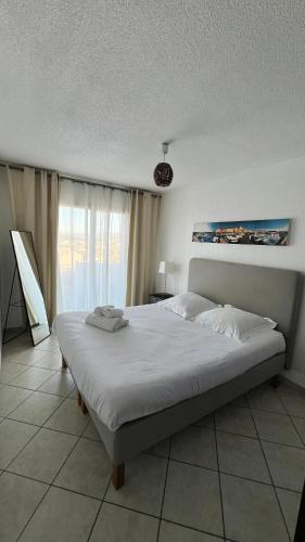 a bedroom with a large white bed in front of a window at Residence Les Jardins De Natallia in La Seyne-sur-Mer