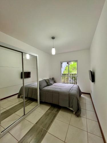 a bedroom with a bed and a large window at Apartamento Icônico em Petrópolis in Petrópolis