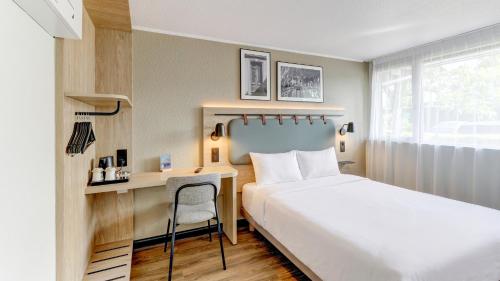 a hotel room with a bed and a desk at Campanile NATURE - Moulins Avermes in Avermes